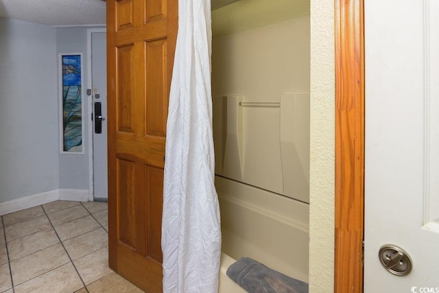 bathroom featuring tile patterned floors, a textured ceiling, baseboards, and shower / bathtub combination with curtain