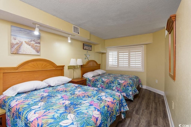 bedroom featuring a textured ceiling, baseboards, visible vents, and wood finished floors