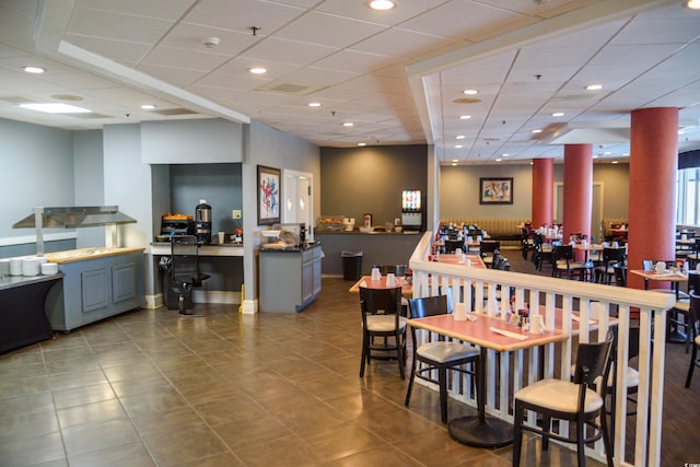 tiled dining area with a paneled ceiling, a bar, and recessed lighting