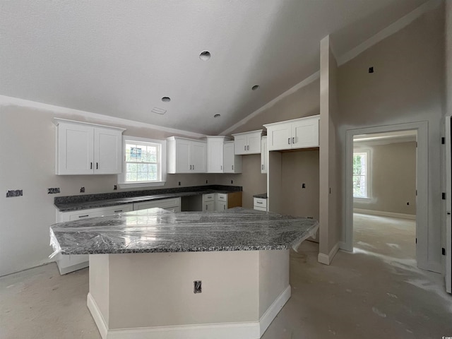 2929 Hughes Gasque Rd, Aynor, SC 29511 - kitchen with lofted ceiling, a center island, white cabinetry, dark stone countertops, and baseboards