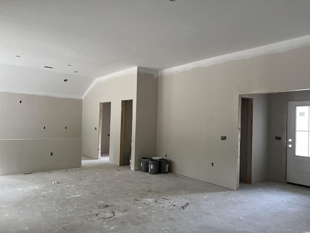 unfurnished living room featuring lofted ceiling and a textured ceiling