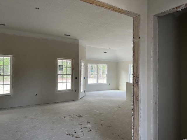 spare room with a textured ceiling, a healthy amount of sunlight, and visible vents