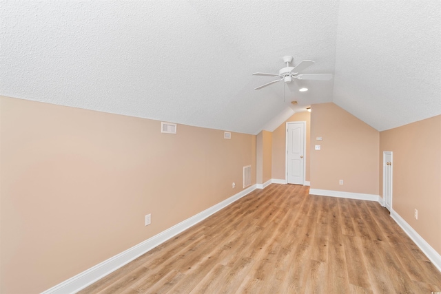 additional living space with light wood-style flooring, visible vents, and a textured ceiling