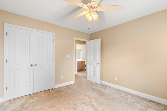 unfurnished bedroom with baseboards, light carpet, a closet, and a ceiling fan