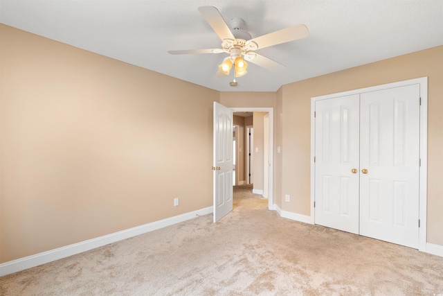 unfurnished bedroom with a ceiling fan, baseboards, a closet, and light carpet