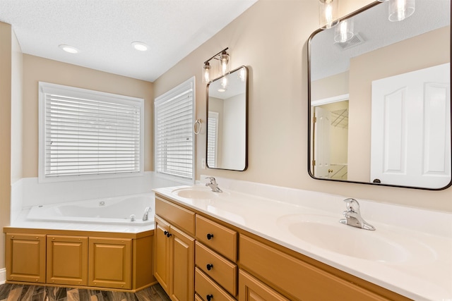 bathroom featuring a bath, visible vents, a textured ceiling, and a sink