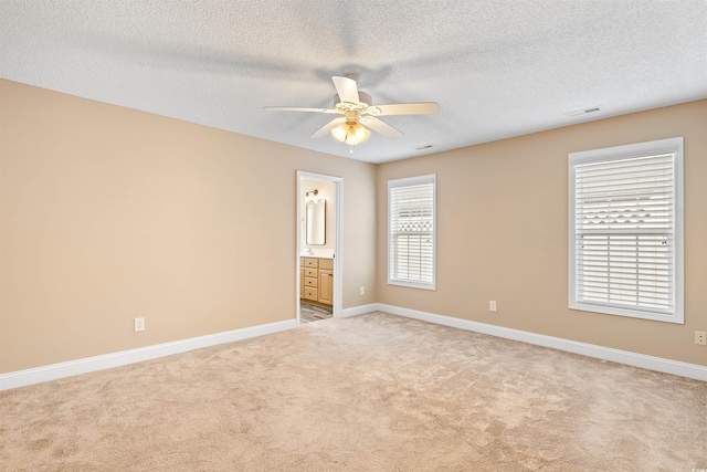 unfurnished room featuring baseboards, light colored carpet, ceiling fan, and a textured ceiling