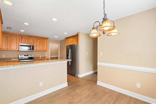 kitchen with light stone countertops, baseboards, light wood-style flooring, a sink, and stainless steel appliances