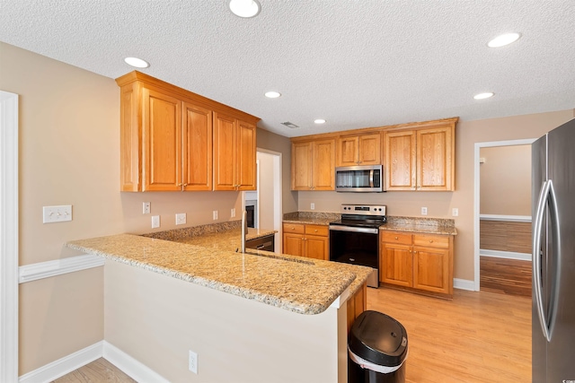 kitchen with a peninsula, light wood-style flooring, recessed lighting, and appliances with stainless steel finishes