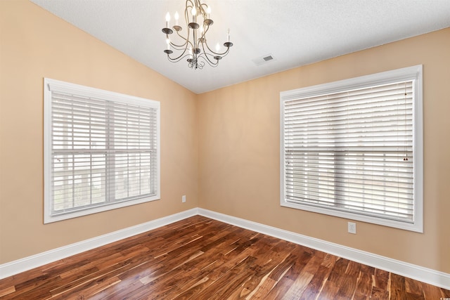 empty room featuring a wealth of natural light, visible vents, a notable chandelier, and vaulted ceiling