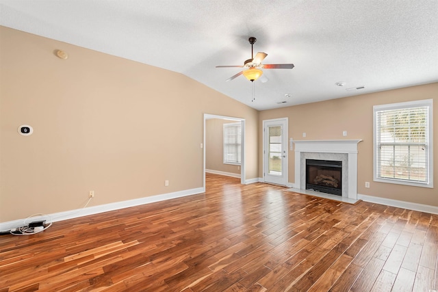 unfurnished living room with lofted ceiling, wood finished floors, baseboards, and ceiling fan