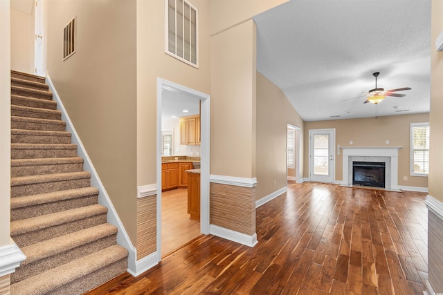 unfurnished living room featuring stairs, visible vents, wood finished floors, and a ceiling fan