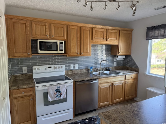 kitchen featuring visible vents, dishwasher, a sink, dark countertops, and white electric range oven