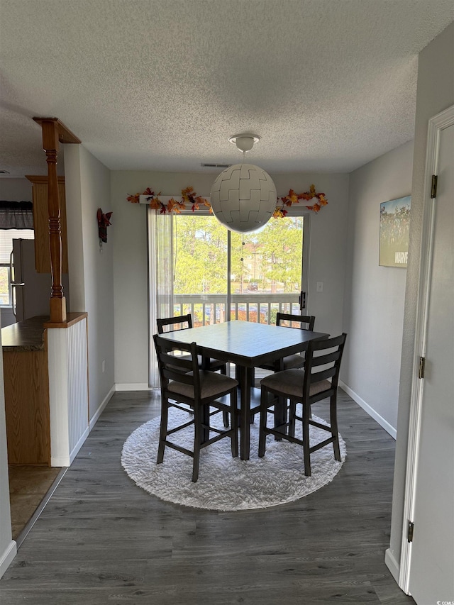 dining room with baseboards, a textured ceiling, and dark wood finished floors