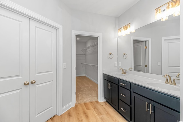 19 Coventry Pl, Pawleys Island, SC 29585 - bathroom with double vanity, wood finished floors, a walk in closet, and baseboards