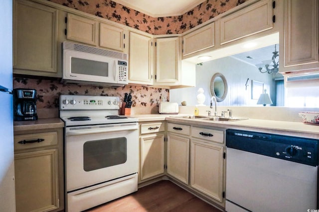 kitchen with a sink, light countertops, white appliances, and a notable chandelier