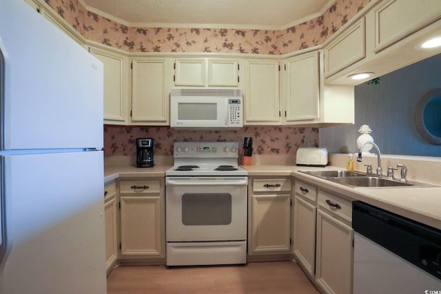 kitchen with a sink, light countertops, light wood finished floors, and white appliances
