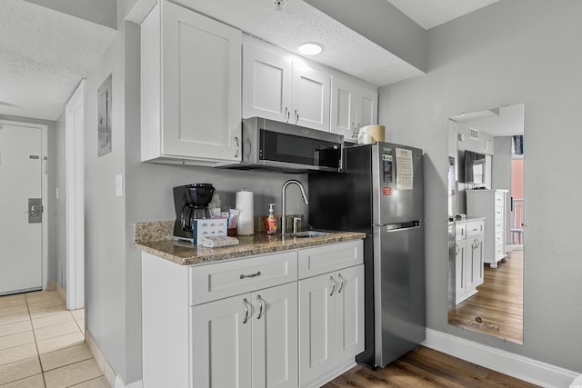 2801 S Ocean Blvd # 231, North Myrtle Beach, SC 29582 - kitchen featuring a textured ceiling, white cabinets, a sink, appliances with stainless steel finishes, and baseboards