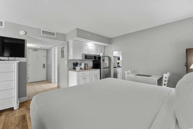 2801 S Ocean Blvd # 231, North Myrtle Beach, SC 29582 - bedroom with light wood-type flooring, visible vents, a sink, and freestanding refrigerator