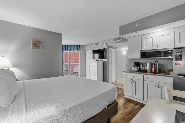 2801 S Ocean Blvd # 231, North Myrtle Beach, SC 29582 - bedroom featuring visible vents, light wood finished floors, freestanding refrigerator, and a sink