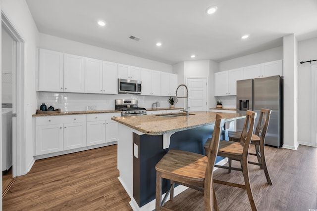204 Leaflet Loop, Pawleys Island, SC 29585 - kitchen featuring stainless steel appliances, a sink, an island with sink, white cabinetry, and wood finished floors