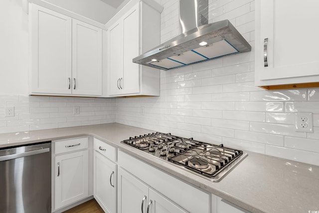 kitchen featuring wall chimney exhaust hood, stainless steel appliances, backsplash, and white cabinetry
