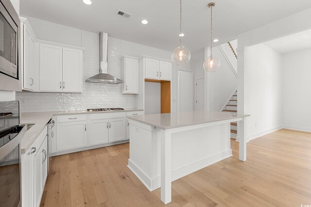 kitchen featuring wall chimney range hood, tasteful backsplash, light wood finished floors, light countertops, and recessed lighting