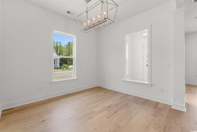 unfurnished dining area featuring a chandelier, light wood finished floors, and baseboards
