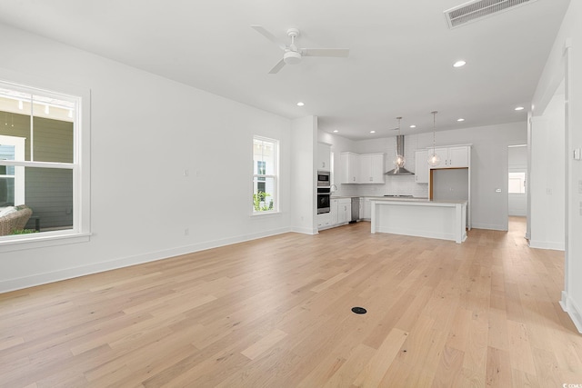unfurnished living room with light wood-style flooring, ceiling fan, baseboards, and recessed lighting