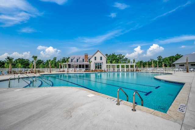 community pool with fence, a patio, and view of wooded area