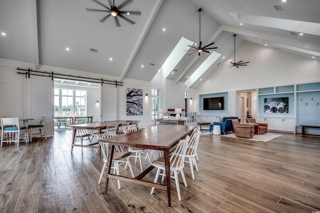 dining room with ceiling fan, high vaulted ceiling, wood finished floors, a skylight, and beam ceiling