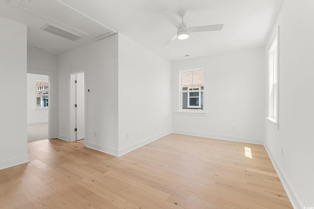 spare room with attic access, light wood-style floors, baseboards, and ceiling fan
