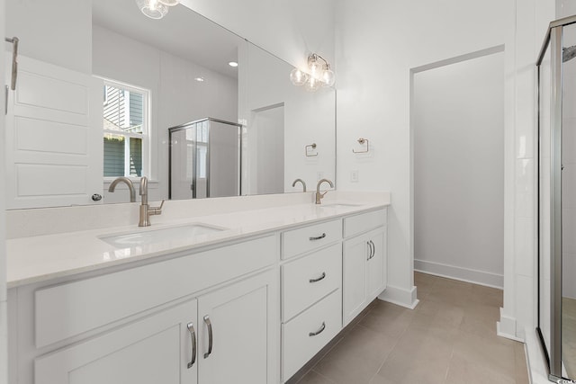 bathroom featuring a stall shower, double vanity, tile patterned floors, and baseboards