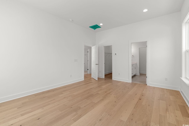 unfurnished bedroom featuring a spacious closet, light wood-style flooring, baseboards, a closet, and recessed lighting