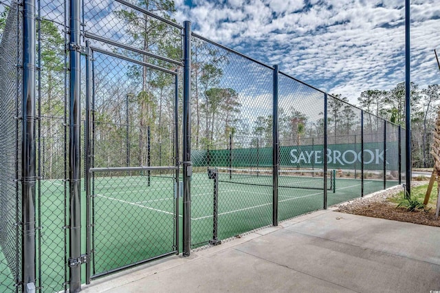 view of tennis court featuring fence and a gate