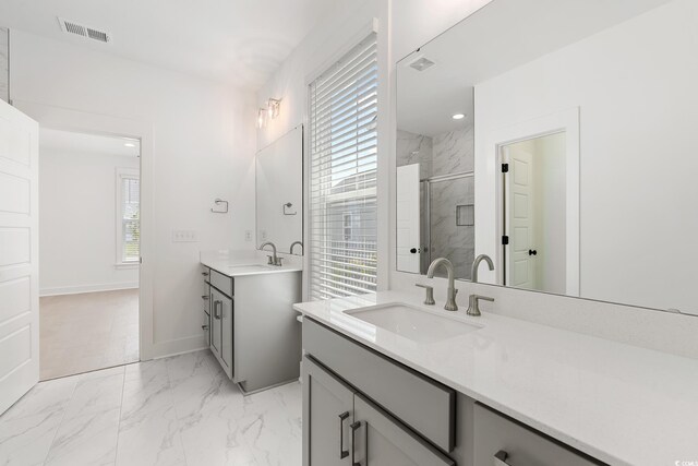 bathroom featuring a marble finish shower, two vanities, marble look tiles, and baseboards