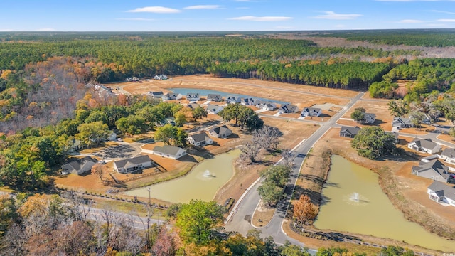 aerial overview of property's location featuring a forest and a nearby body of water