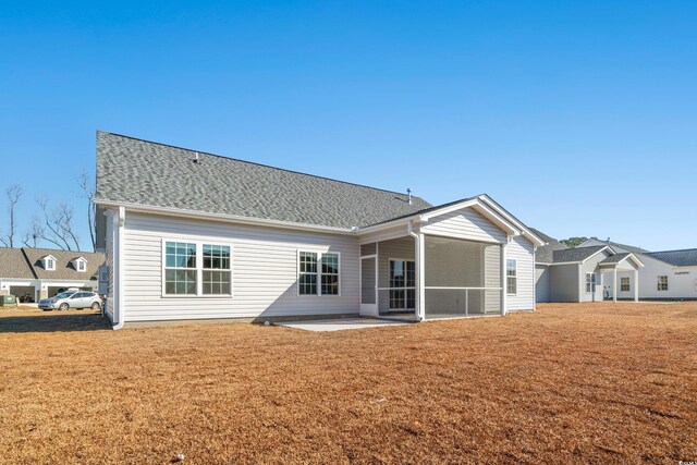 rear view of property with a lawn, a sunroom, and roof with shingles