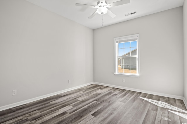 spare room with wood finished floors, a ceiling fan, and baseboards