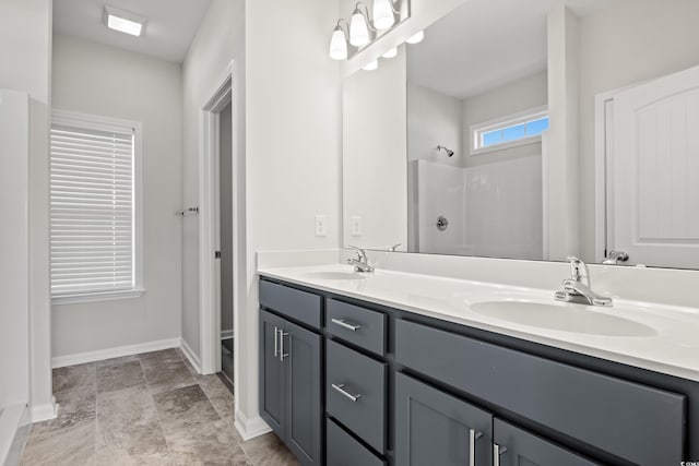 full bathroom with a shower, baseboards, and double vanity