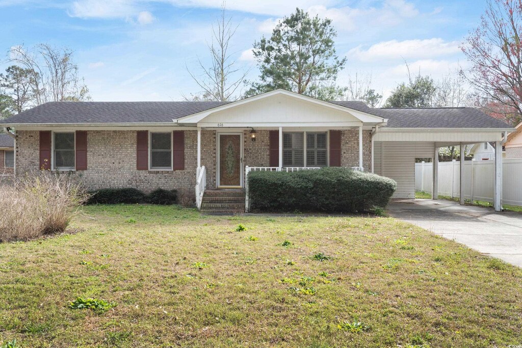 single story home with a porch, a carport, a front lawn, concrete driveway, and brick siding