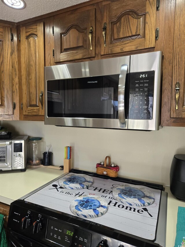 4242 Pinehurst Cir Unit N4, Little River, SC 29566 - kitchen with stainless steel microwave, black stove, light countertops, and brown cabinets