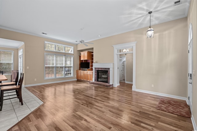 192 Berkshire Loop, Pawleys Island, SC 29585 - unfurnished living room featuring light wood-style flooring, crown molding, ceiling fan, and a fireplace
