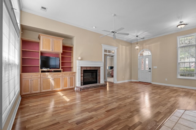 192 Berkshire Loop, Pawleys Island, SC 29585 - unfurnished living room with light wood-type flooring, crown molding, a ceiling fan, a brick fireplace, and baseboards