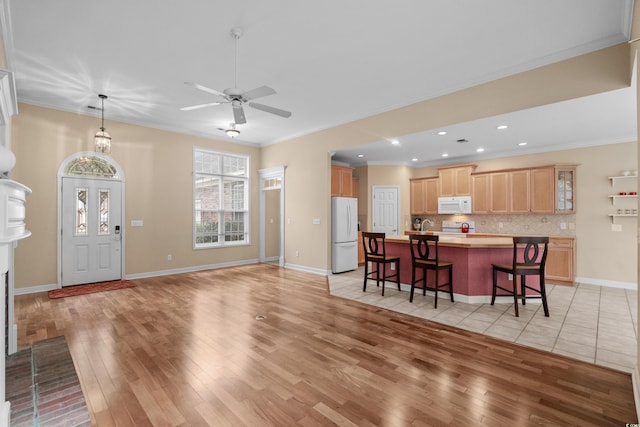 192 Berkshire Loop, Pawleys Island, SC 29585 - kitchen with white appliances, light wood finished floors, light brown cabinetry, a kitchen bar, and light countertops