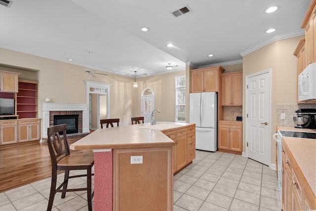 192 Berkshire Loop, Pawleys Island, SC 29585 - kitchen with white appliances, a sink, light tile patterned flooring, a brick fireplace, and a breakfast bar area
