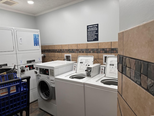 2001 S Ocean Blvd Unit 621, Myrtle Beach, SC 29577 - common laundry area featuring independent washer and dryer, visible vents, tile walls, ornamental molding, and stacked washer and clothes dryer