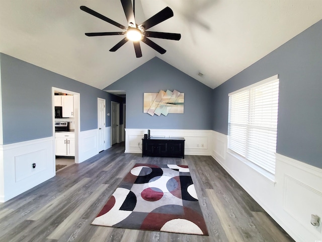 home office featuring a ceiling fan, dark wood-type flooring, a wainscoted wall, and vaulted ceiling