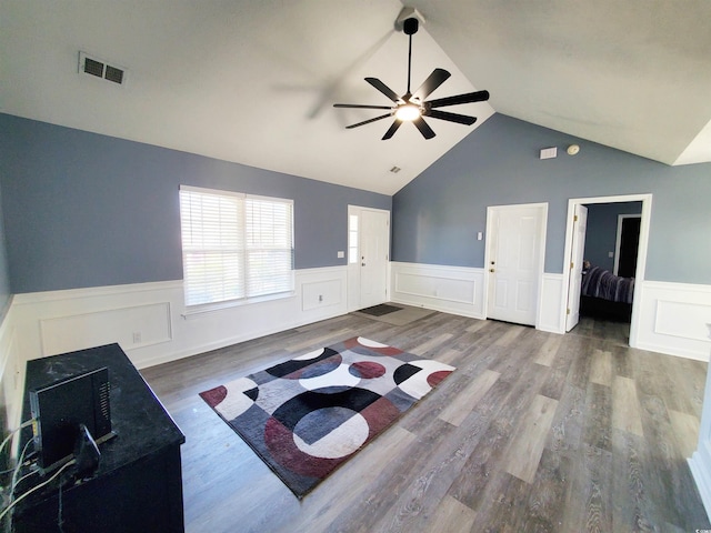 living room with ceiling fan, a wainscoted wall, lofted ceiling, and wood finished floors