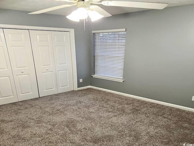 unfurnished bedroom with carpet flooring, a closet, baseboards, and a ceiling fan